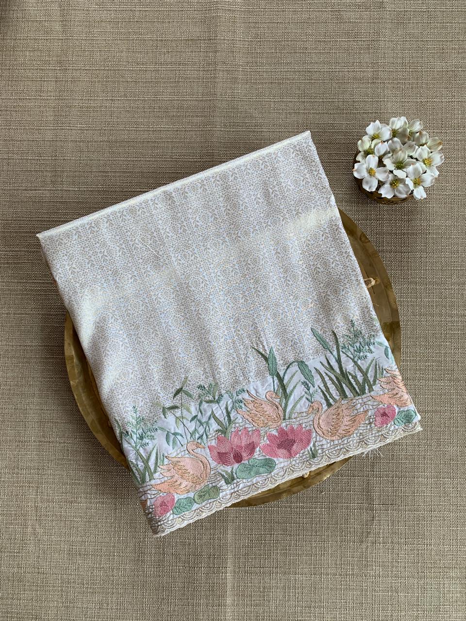 White Kanjeevaram Brocade Saree With Beautiful Pond Theme Embroidered Border.